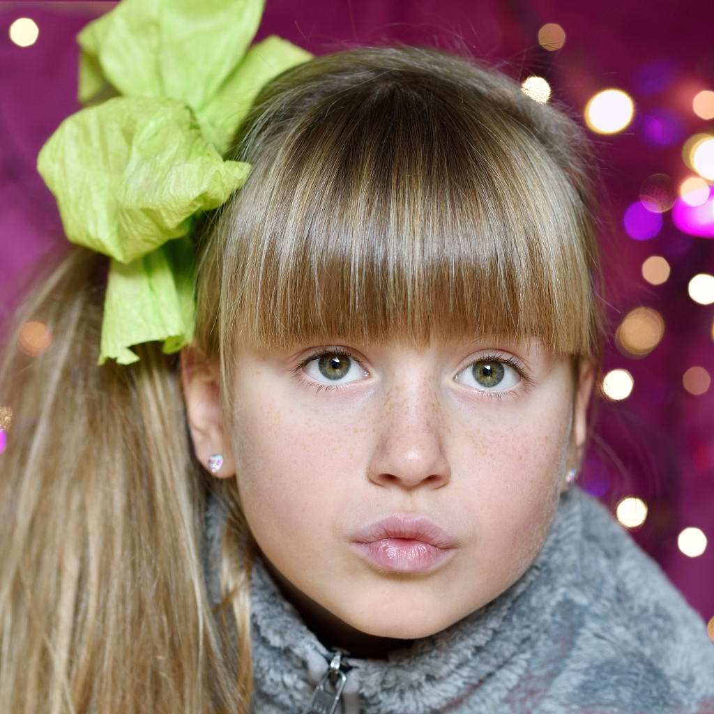 Лицо зеленоглазой девушки с бантом на голове 