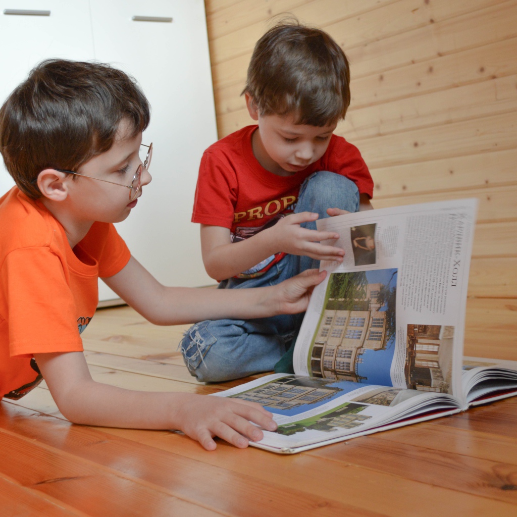 Два маленьких мальчика с книгой  на полу
