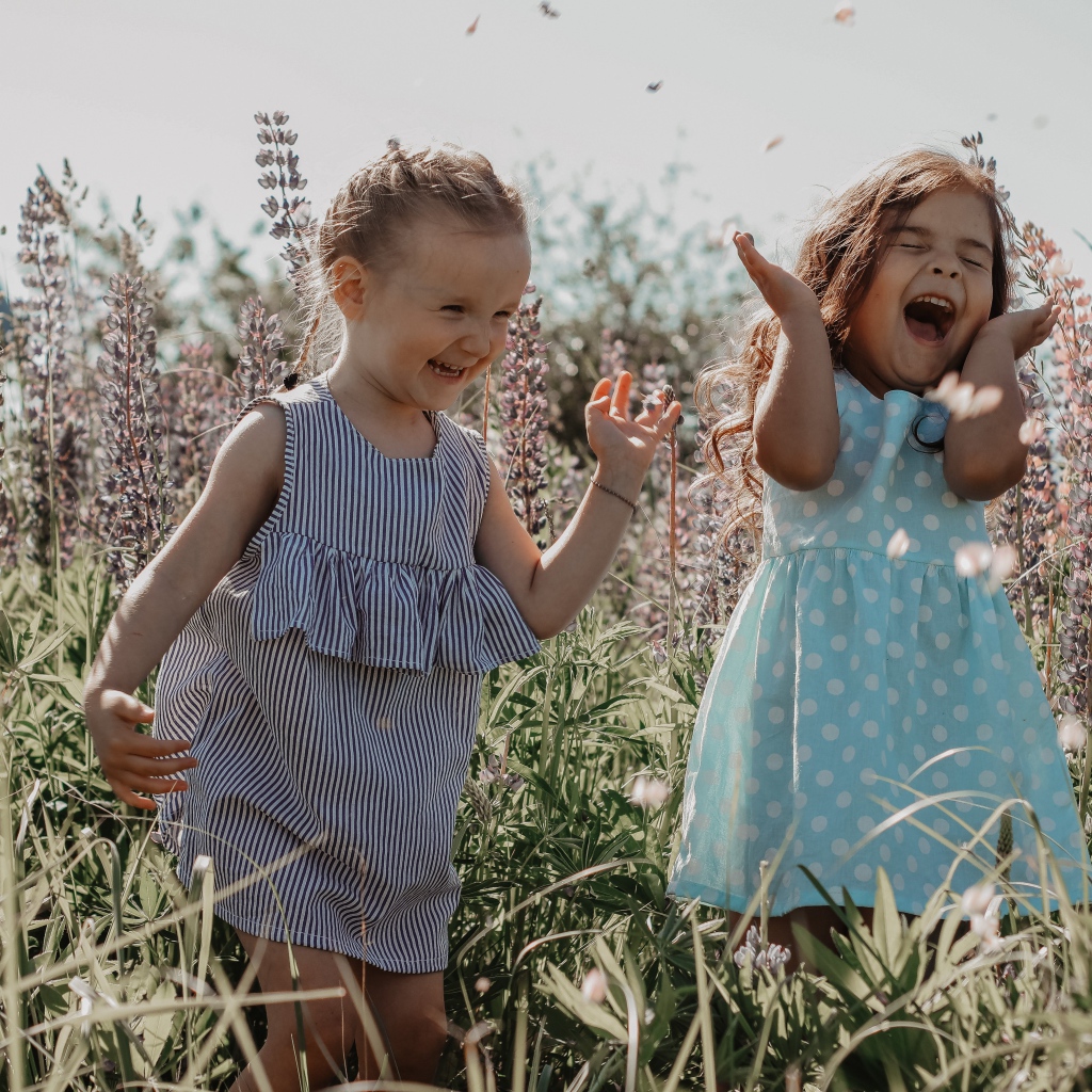 Две маленькие веселые девочки в цветах 