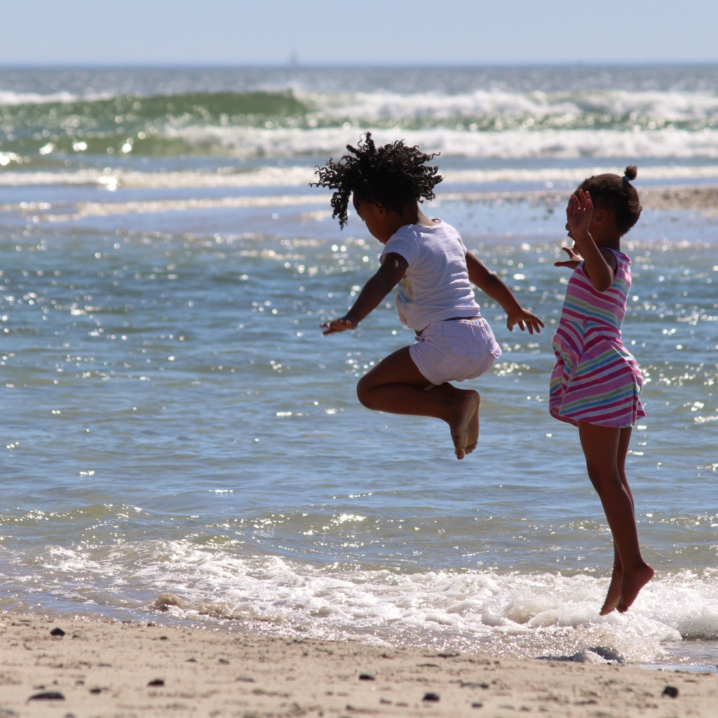 Две маленькие девочки играют на морском берегу