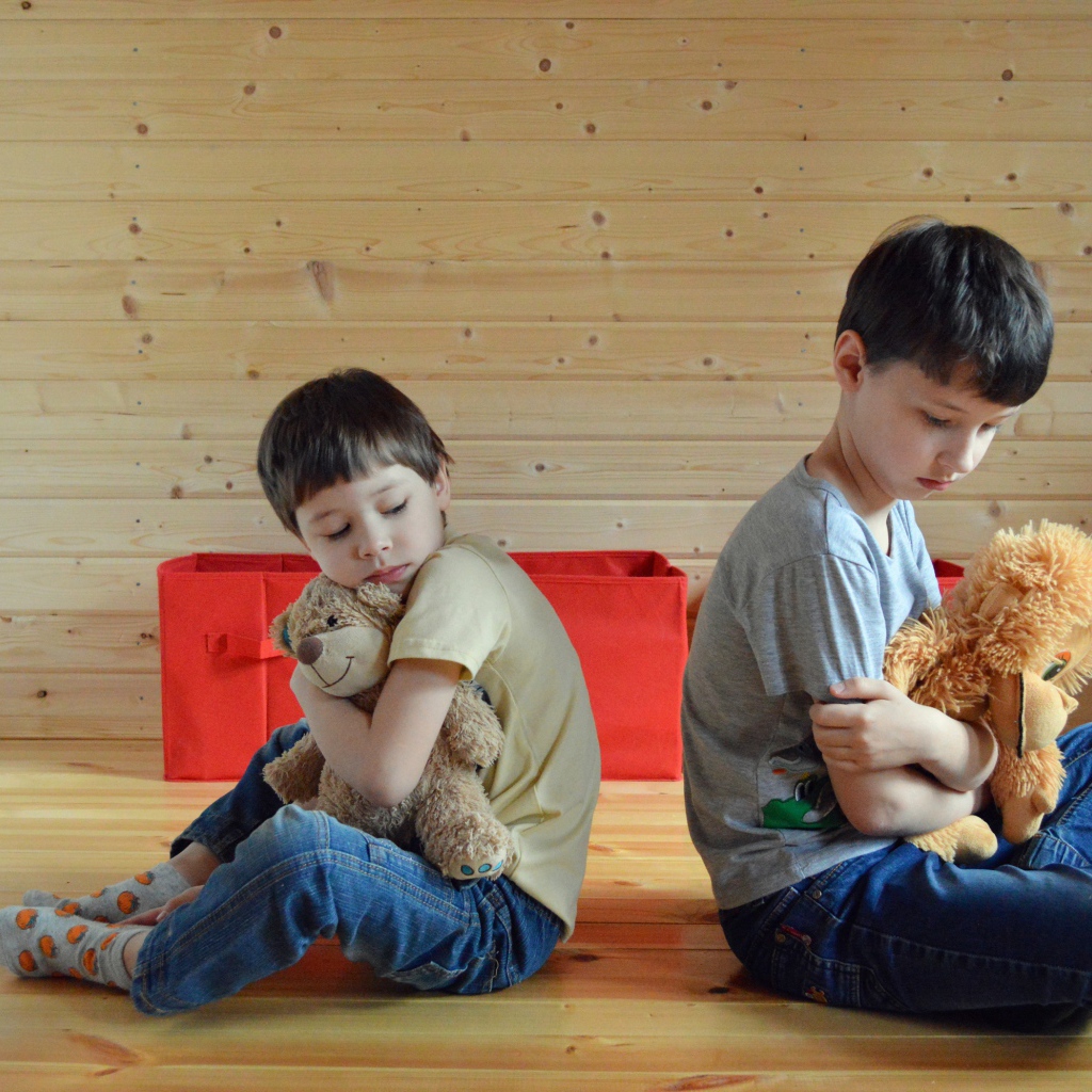 Два маленьких обиженных мальчика сидит на земле