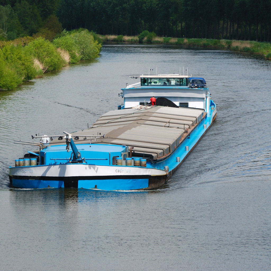 Грузовая баржа плывет по реке 