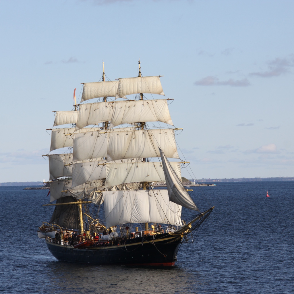 Большой черный корабль с белыми парусами в море