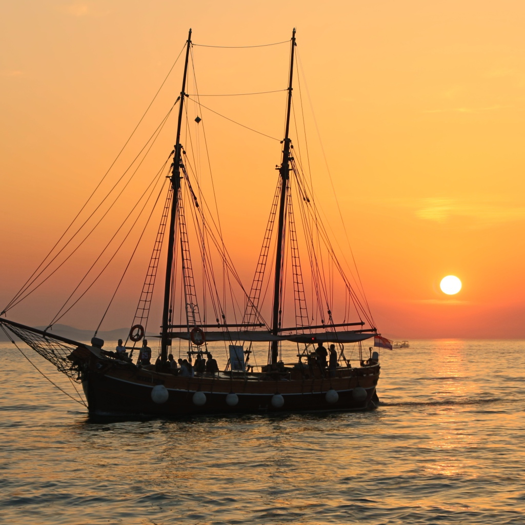 Large ship with lowered sails at sunset