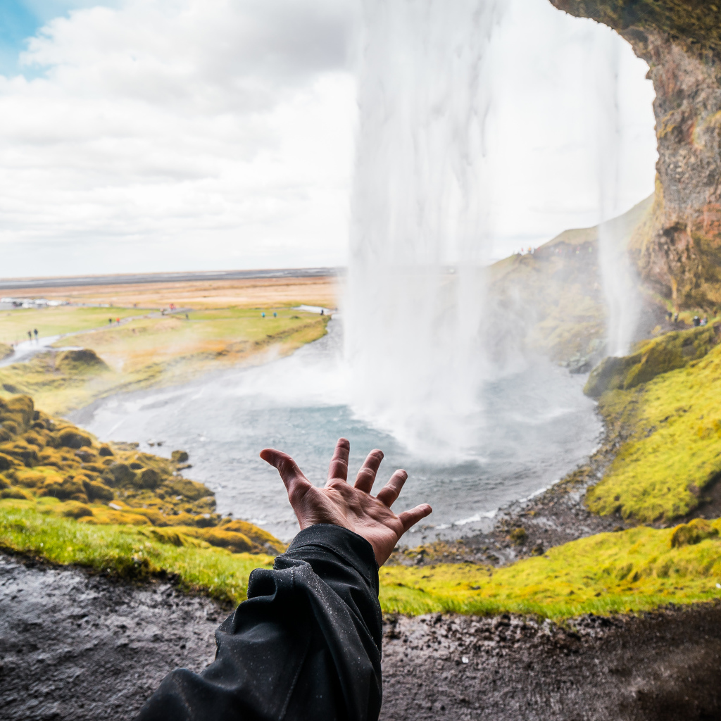 Рука тянется к водопаду Сельяландсфосс, Исландия