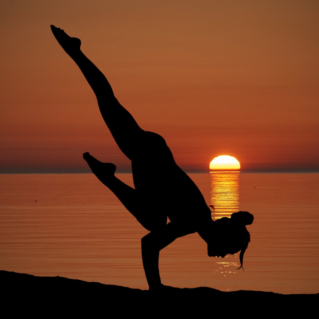 Девушка занимается йогой на закате солнца