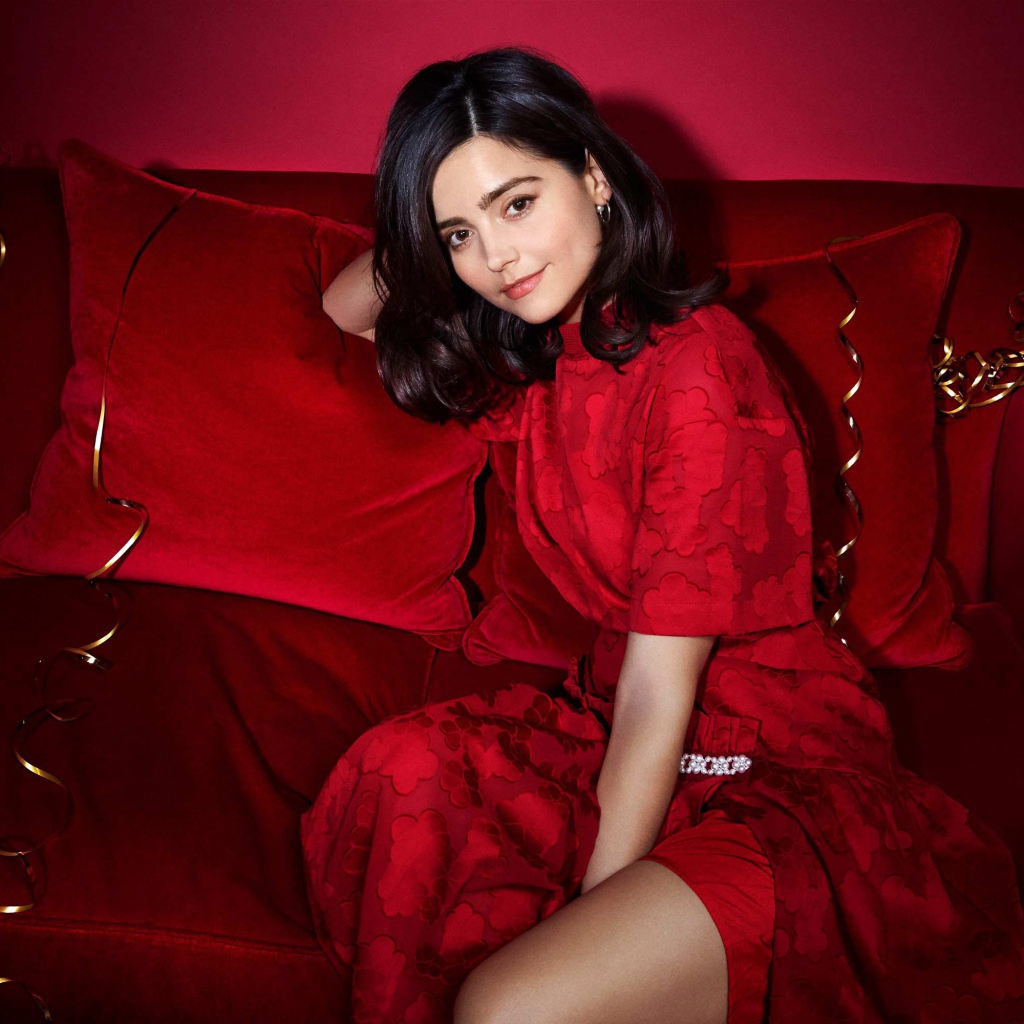 Красивая британская актриса Дженна Коулман сидит на красном диване