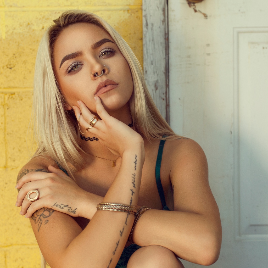 Красивая девушка в татуировках с пирсингом в носу 