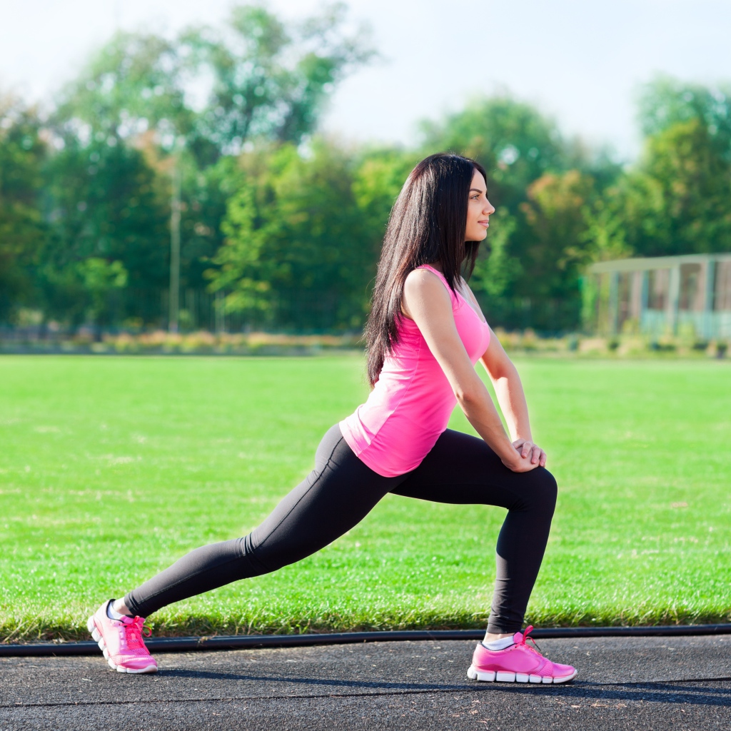 Девушка делает растяжку на поле 