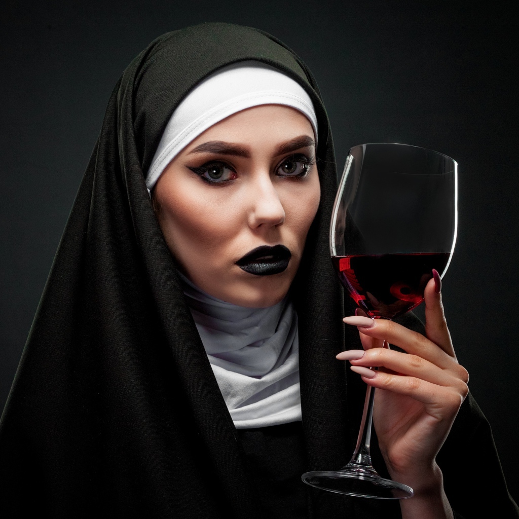 Девушка в костюме монашки с бокалом в руке