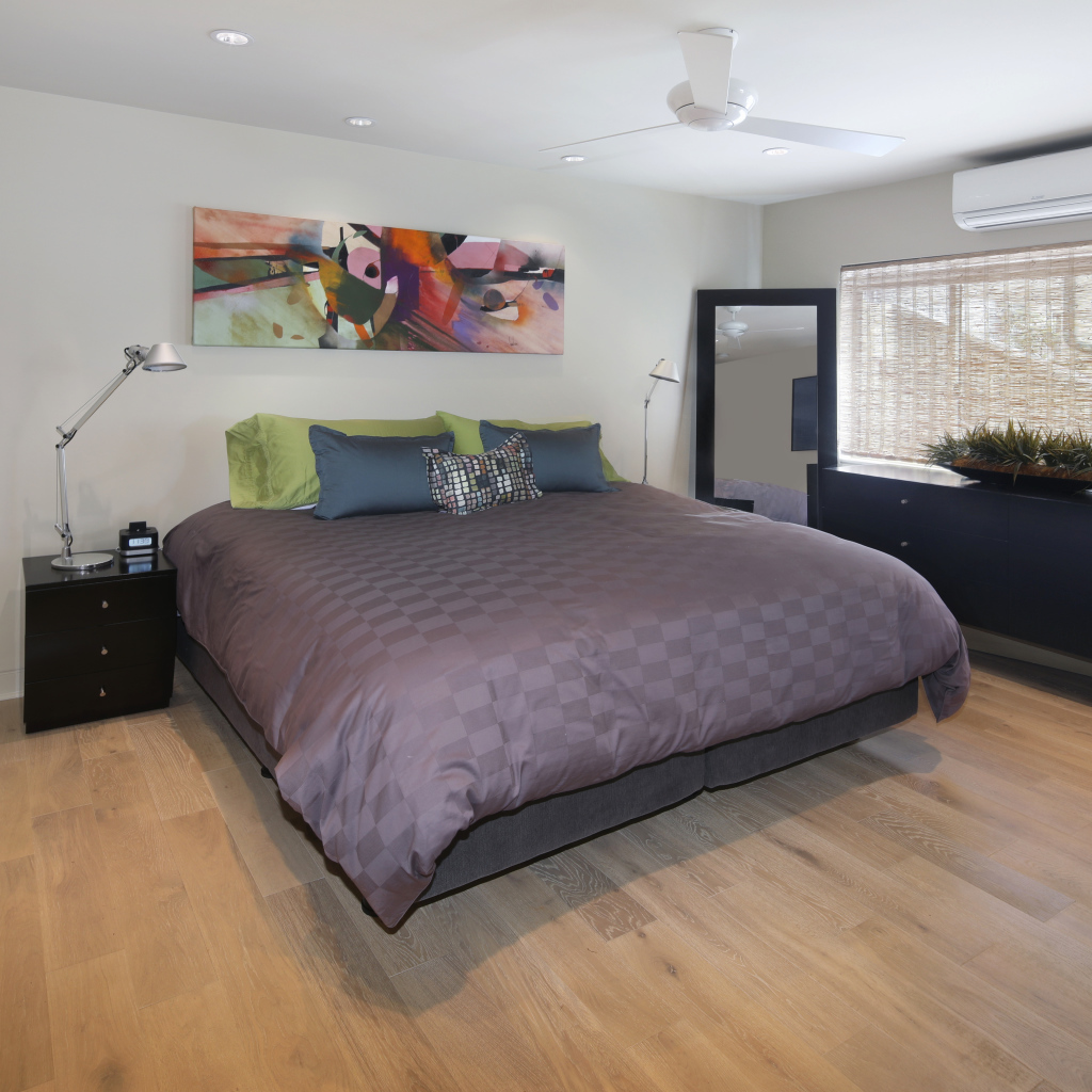 Большая серая кровать в спальне с белыми стенами