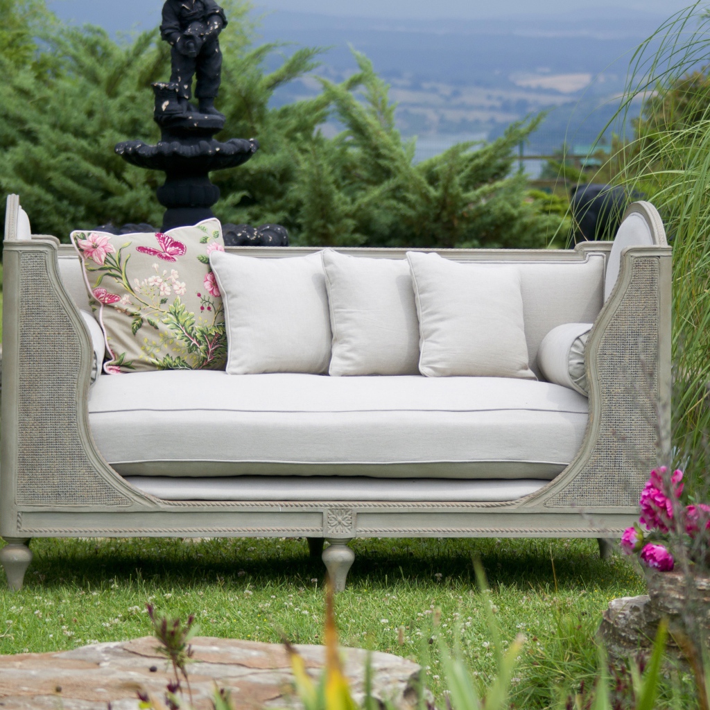 Большой серый диван в саду у пруда 