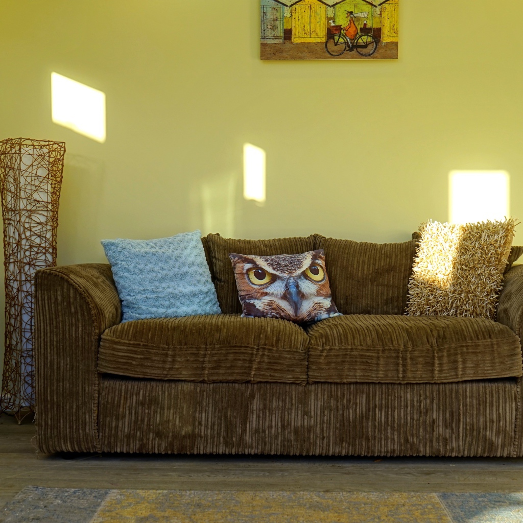 Большой старый диван в комнате с желтыми стенами