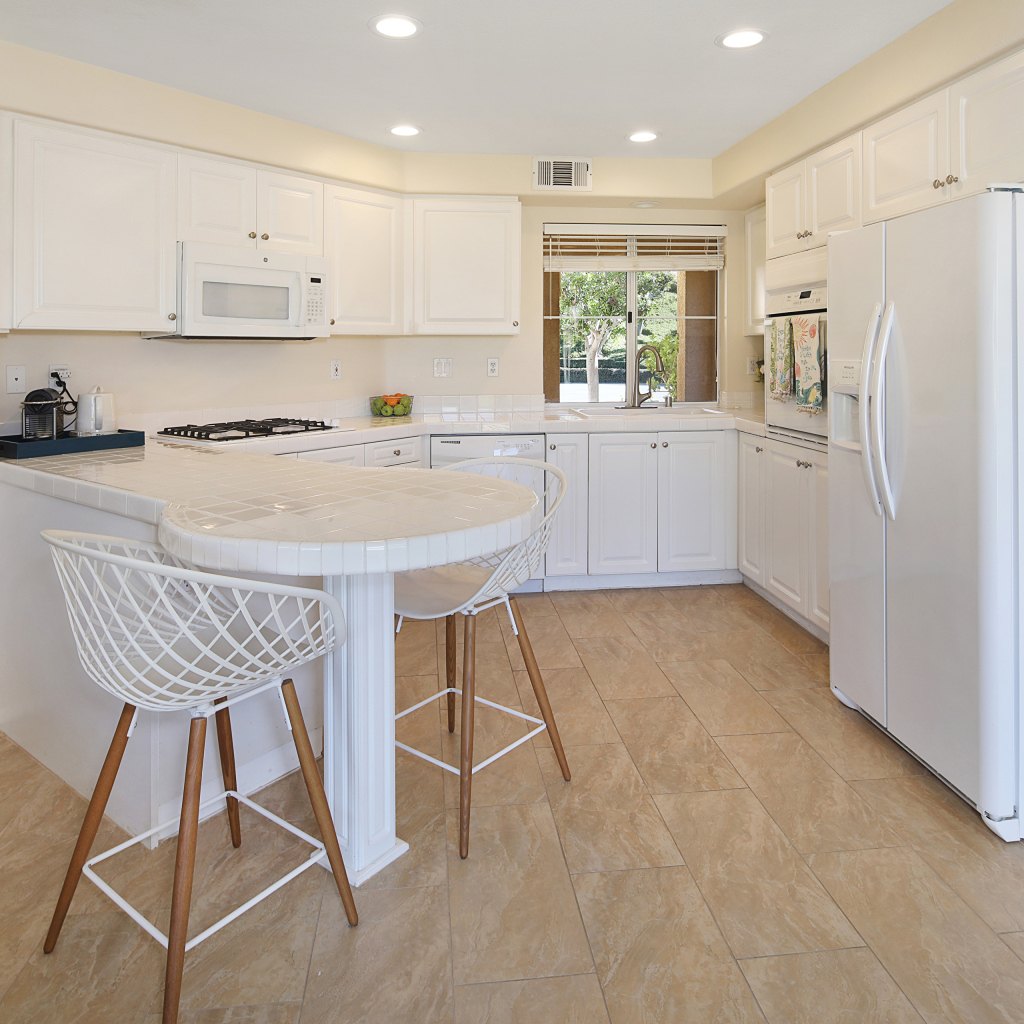 Большой холодильник и белая мебель на кухне 