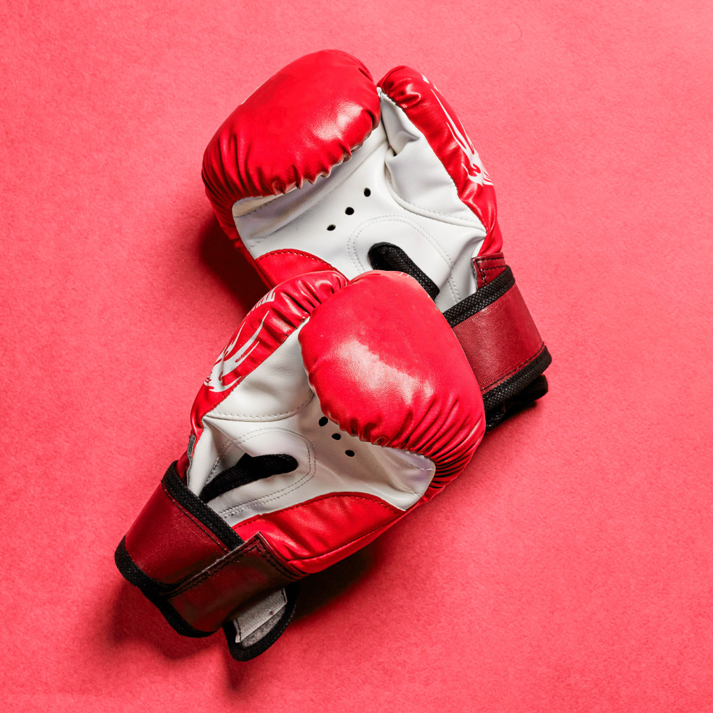 Красные боксерские перчатки на розовом фоне 