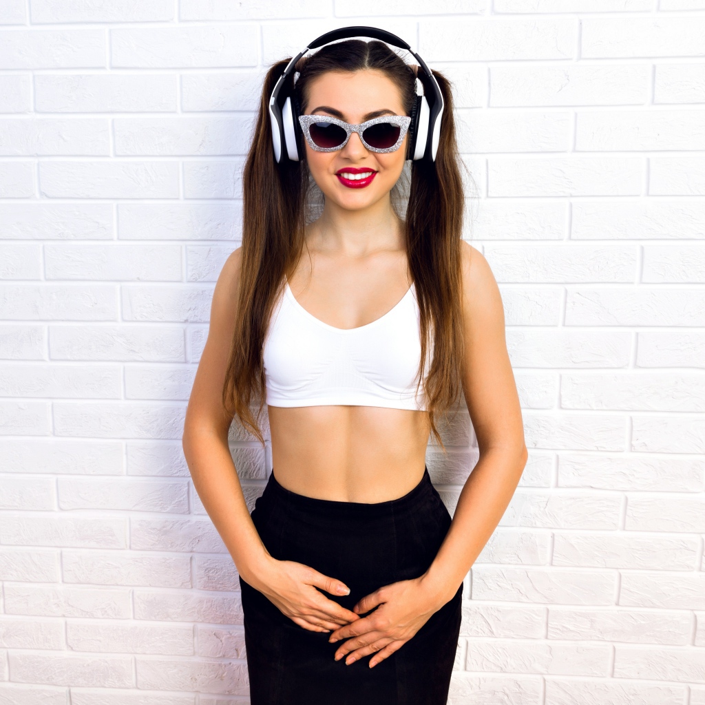 Спортивная девушка в очках у стены