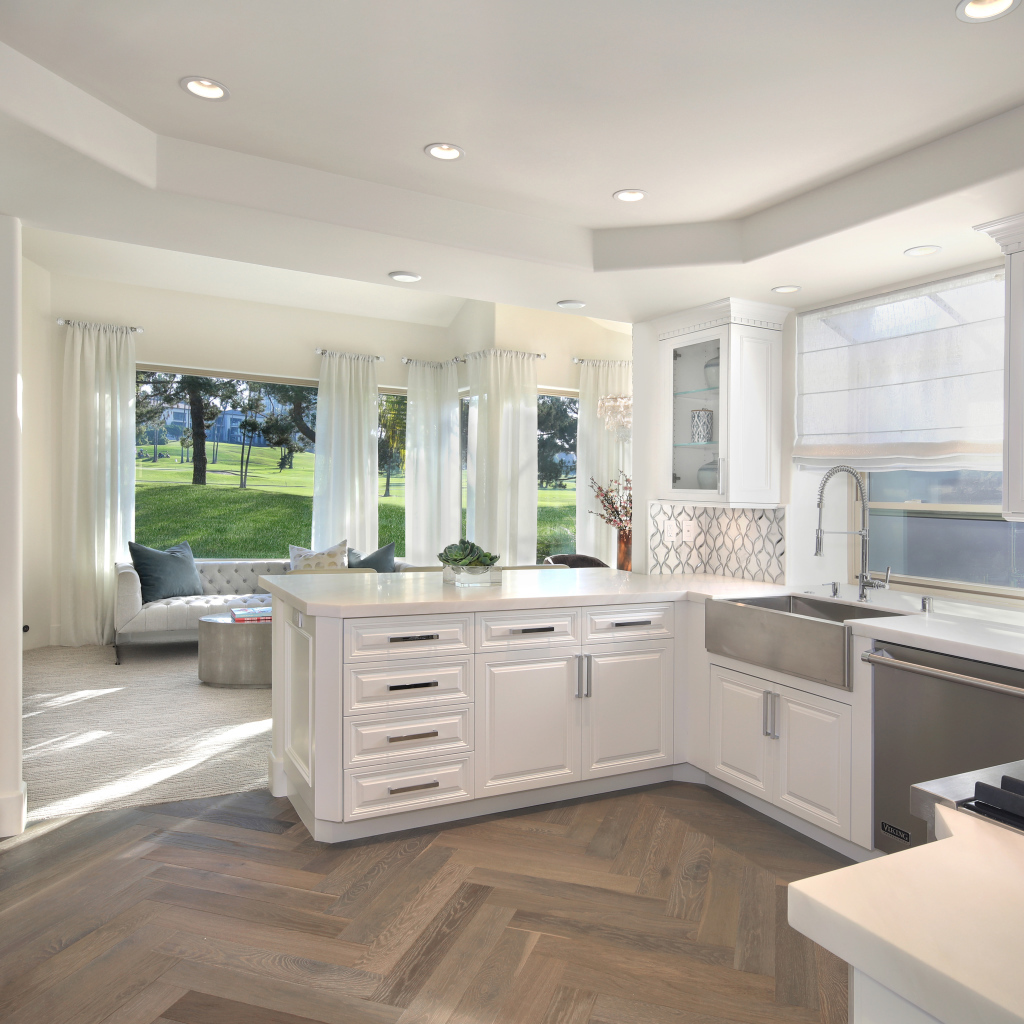 Белый кухонный гарнитур в комнате с большим окном