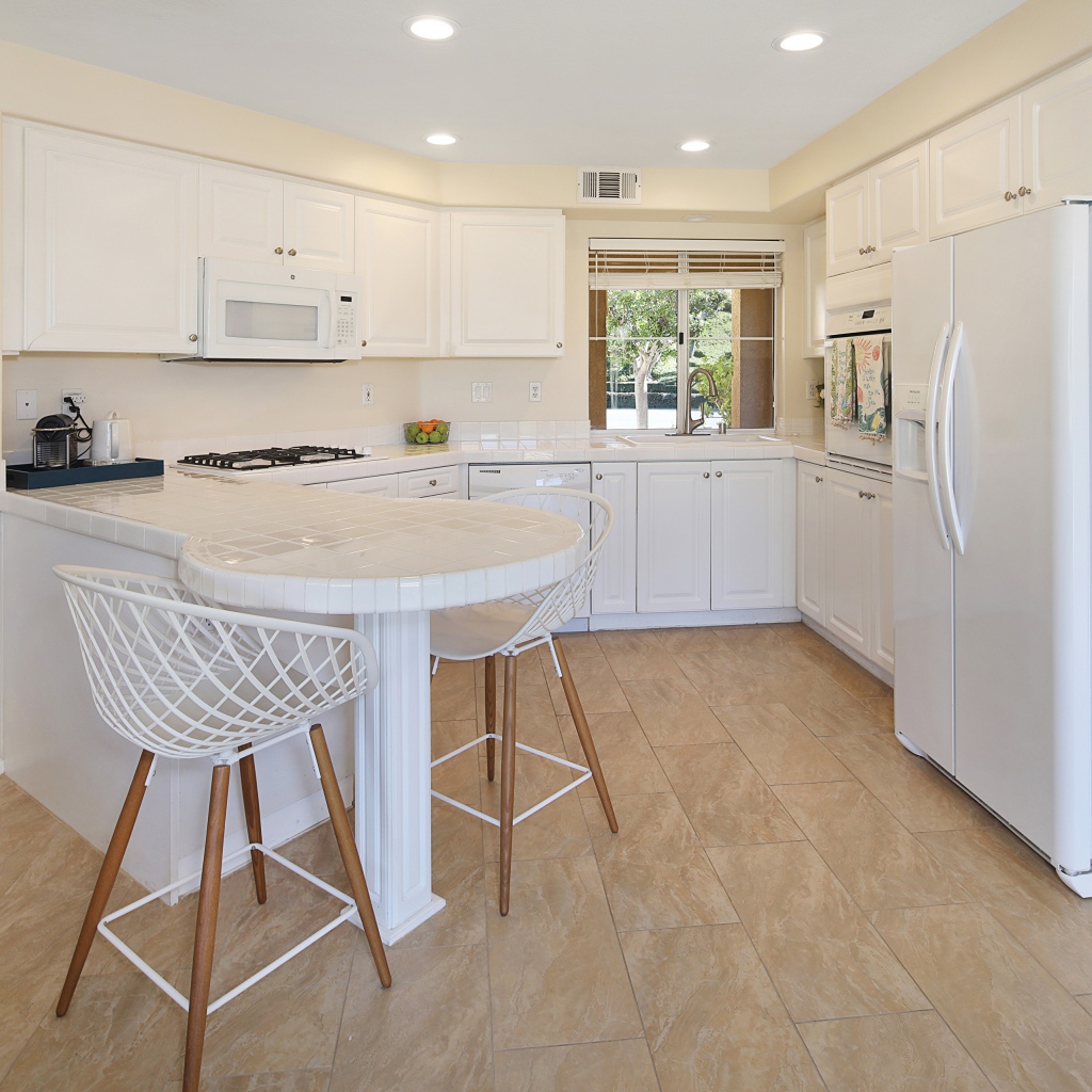 Белая стильная мебель с большим холодильником на кухне