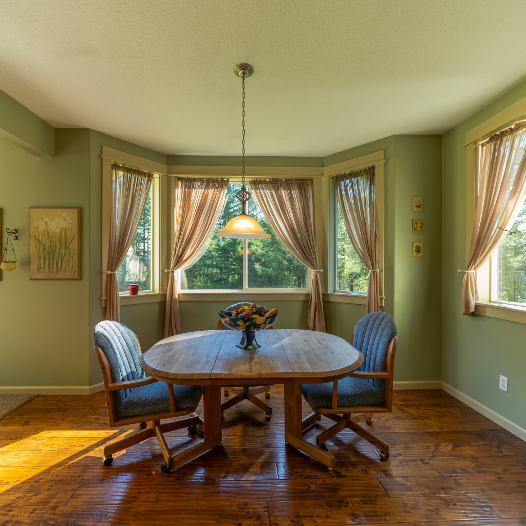 Деревянный стол стоит в гостиной с зелеными стенами