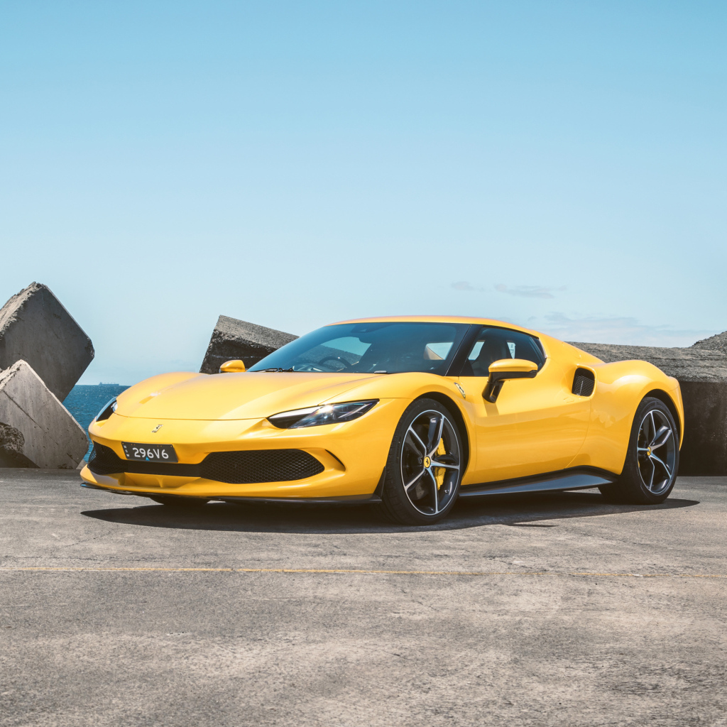 Желтый автомобиль Ferrari 296 GTB у камней