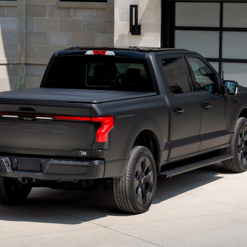 Черный пикап Ford F-150, 2024 года стоит у гаража