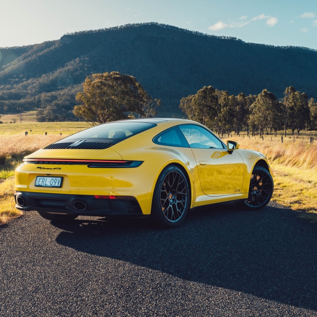 Желтый автомобиль Porsche 911 Carrera GTS вид сзади