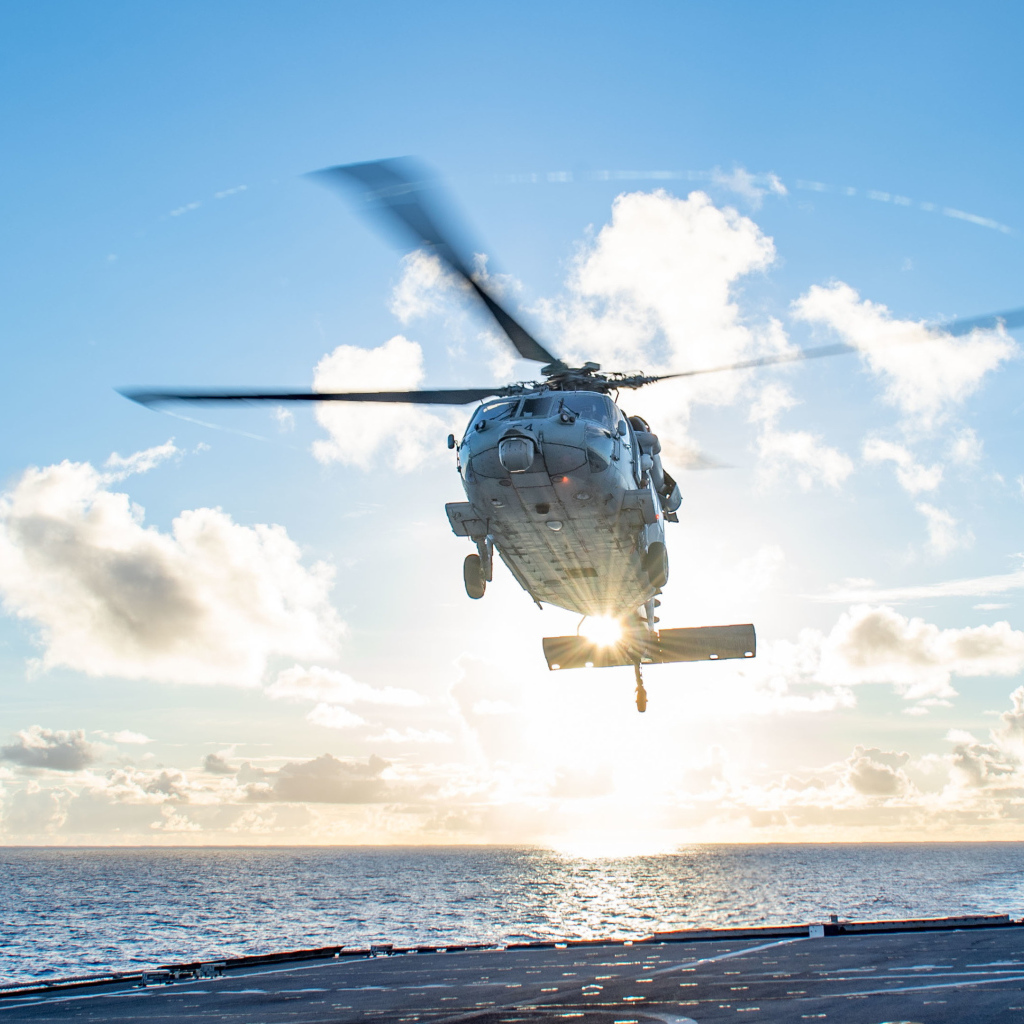 Военный вертолет приземляется на корабль в море