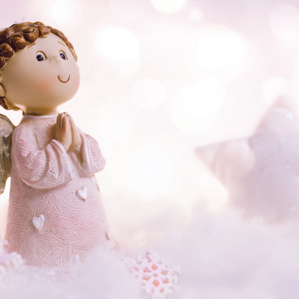 Маленькая статуэтка ангела стоит на снегу