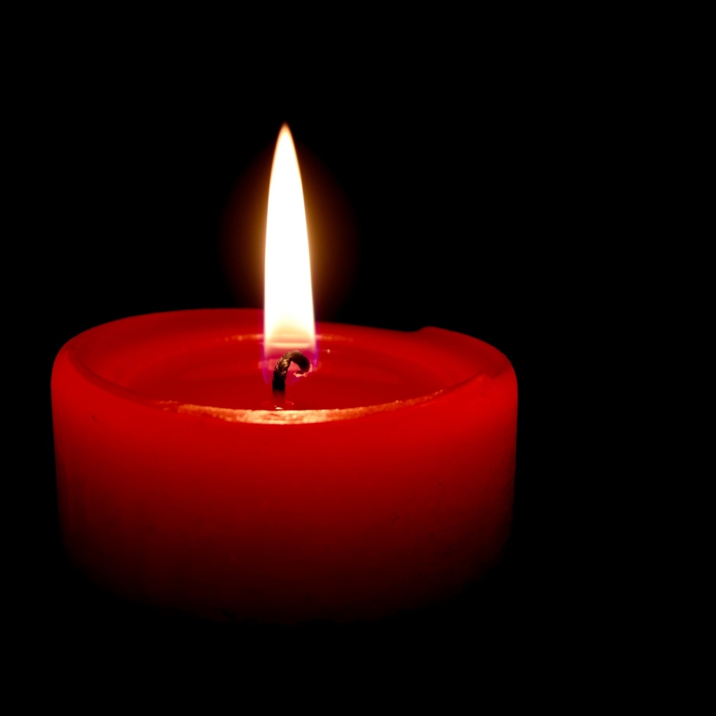 Зажженная красная свеча на черном фоне