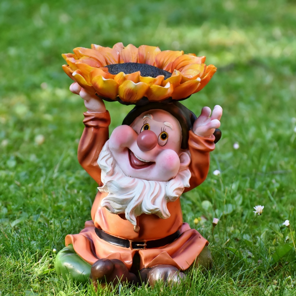 Садовая фигура гном за зеленой траве