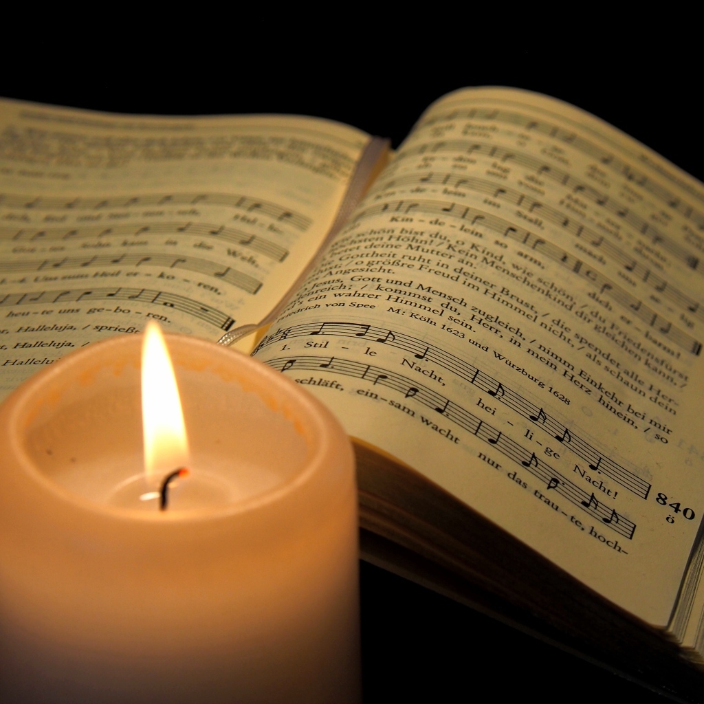 Зажженная свеча с книгой с нотами