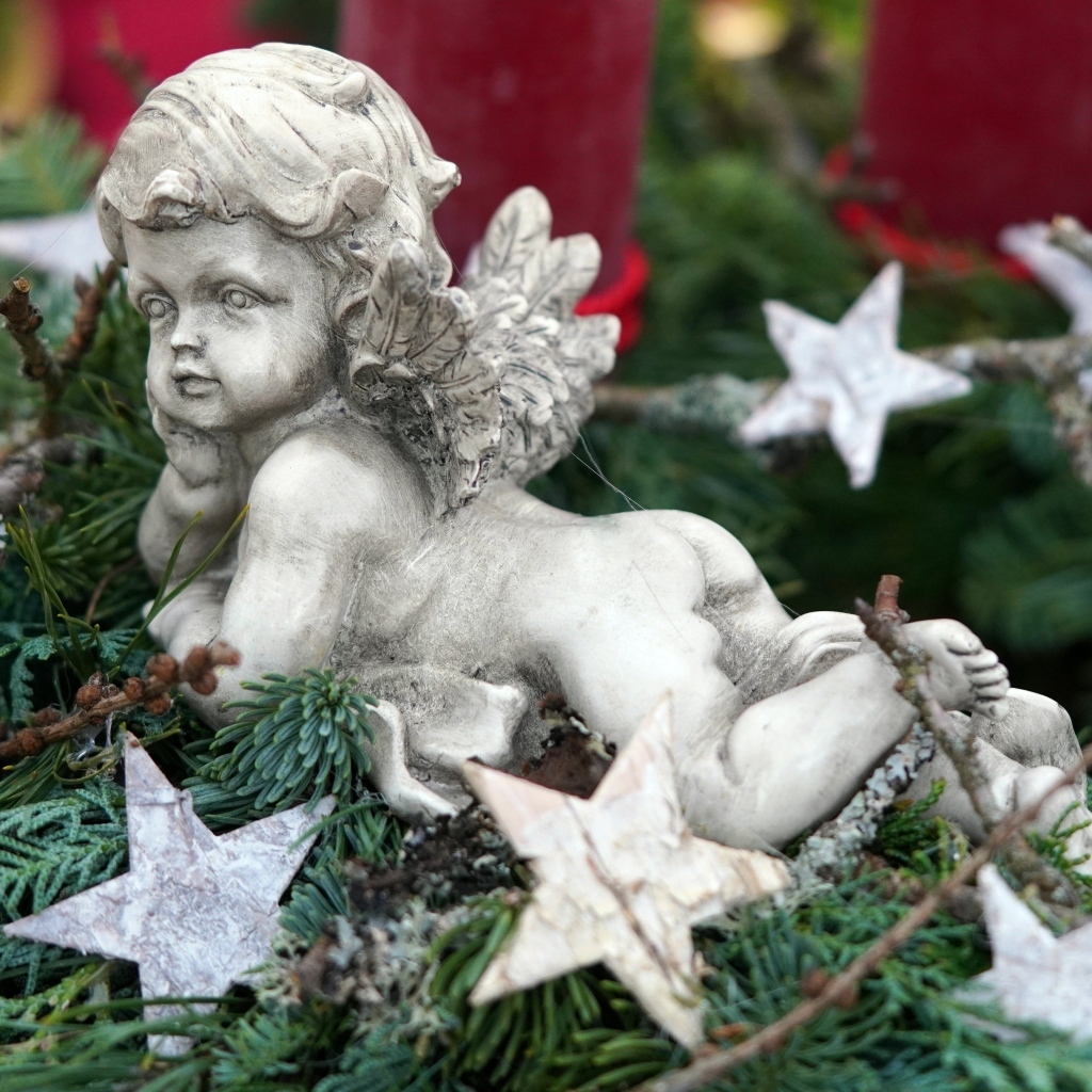 Статуэтка ангел лежит на ветках туи