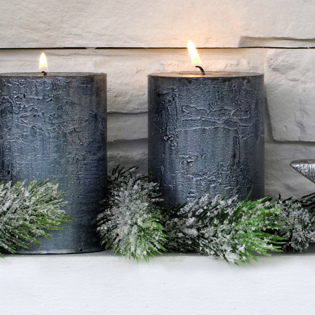 Две большие зажженные свечи у стены