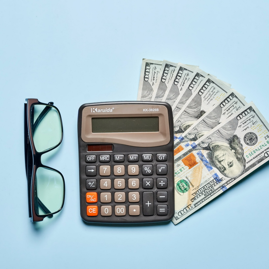 Калькулятор, очки и доллары на голубом фоне