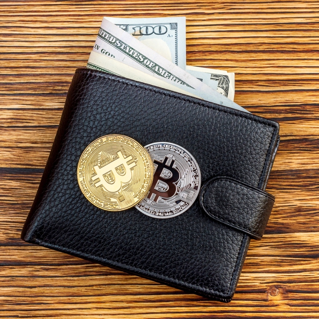 Черный кожаный кошелек с долларами и монетами биткоин