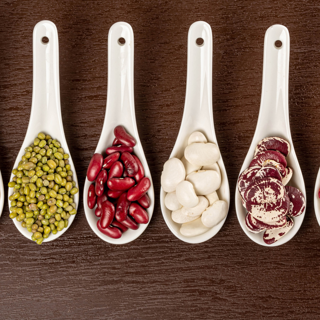 Бобовые зерна в белых ложках на столе