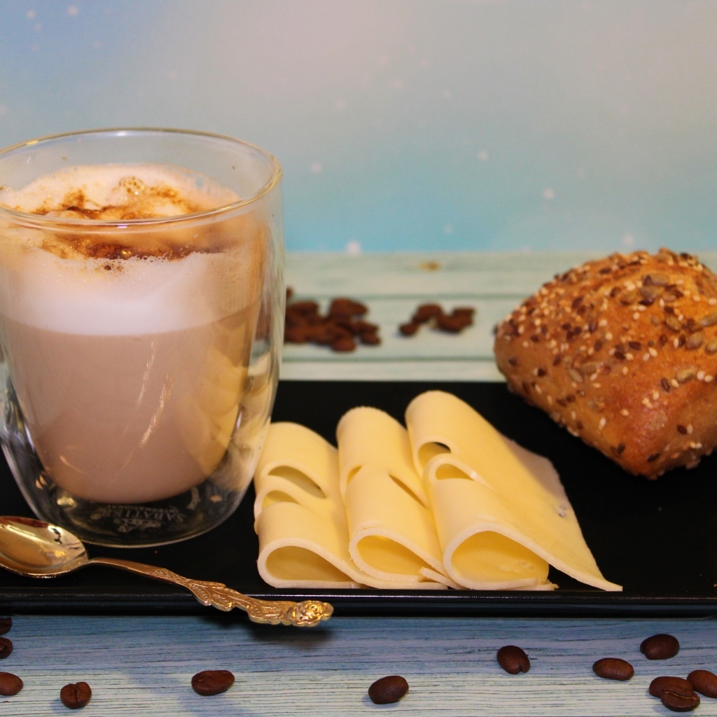 Сыр на тарелке с какао и булочкой