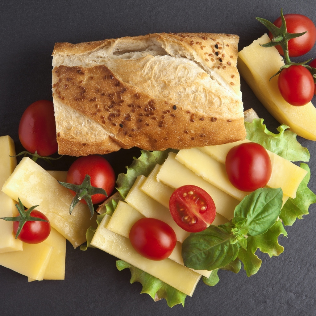 Сыр с батоном и помидорами на столе