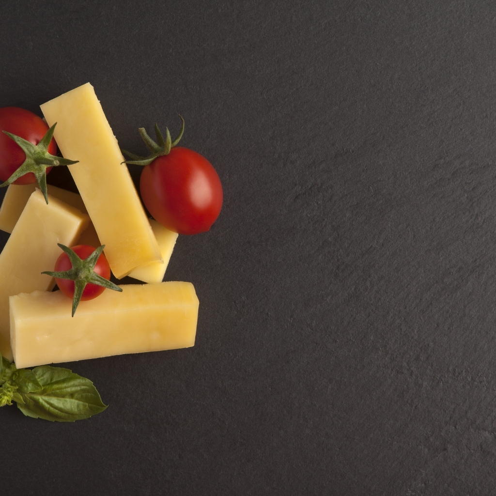 Сыр с помидорами и листьями базилика на сером столе