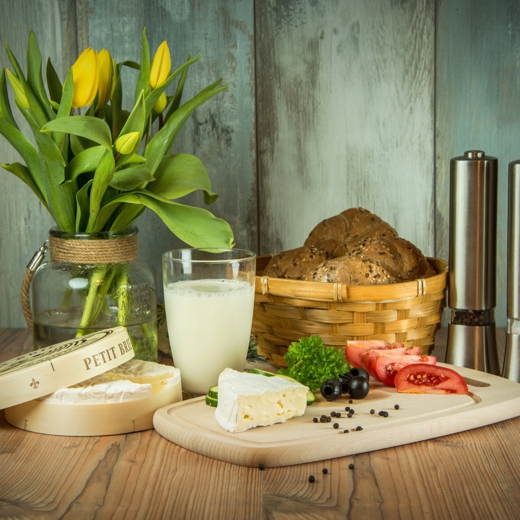 Сыр с овощами на столе с хлебом и букетом тюльпанов