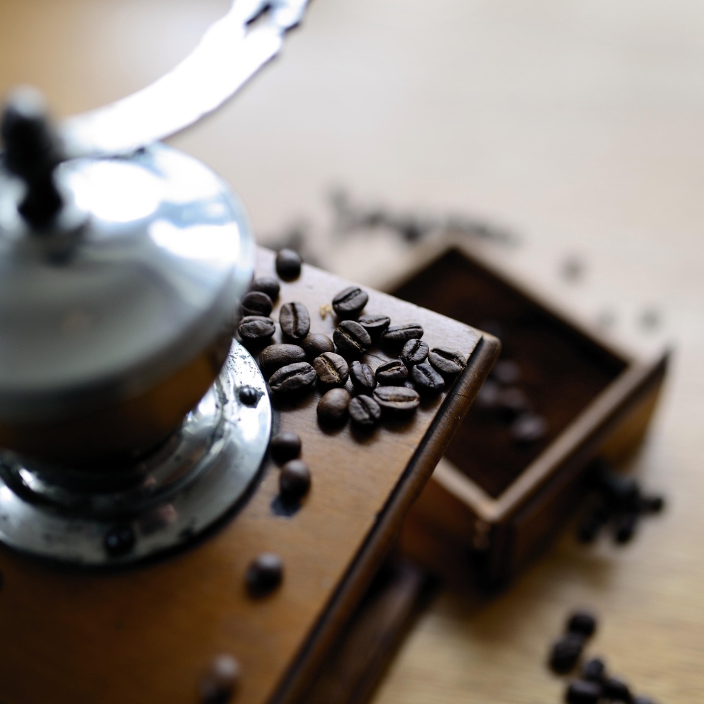 Кофемолка на столе с зернами