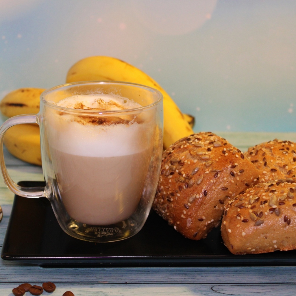 Чашка какао на столе с булочками и бананами