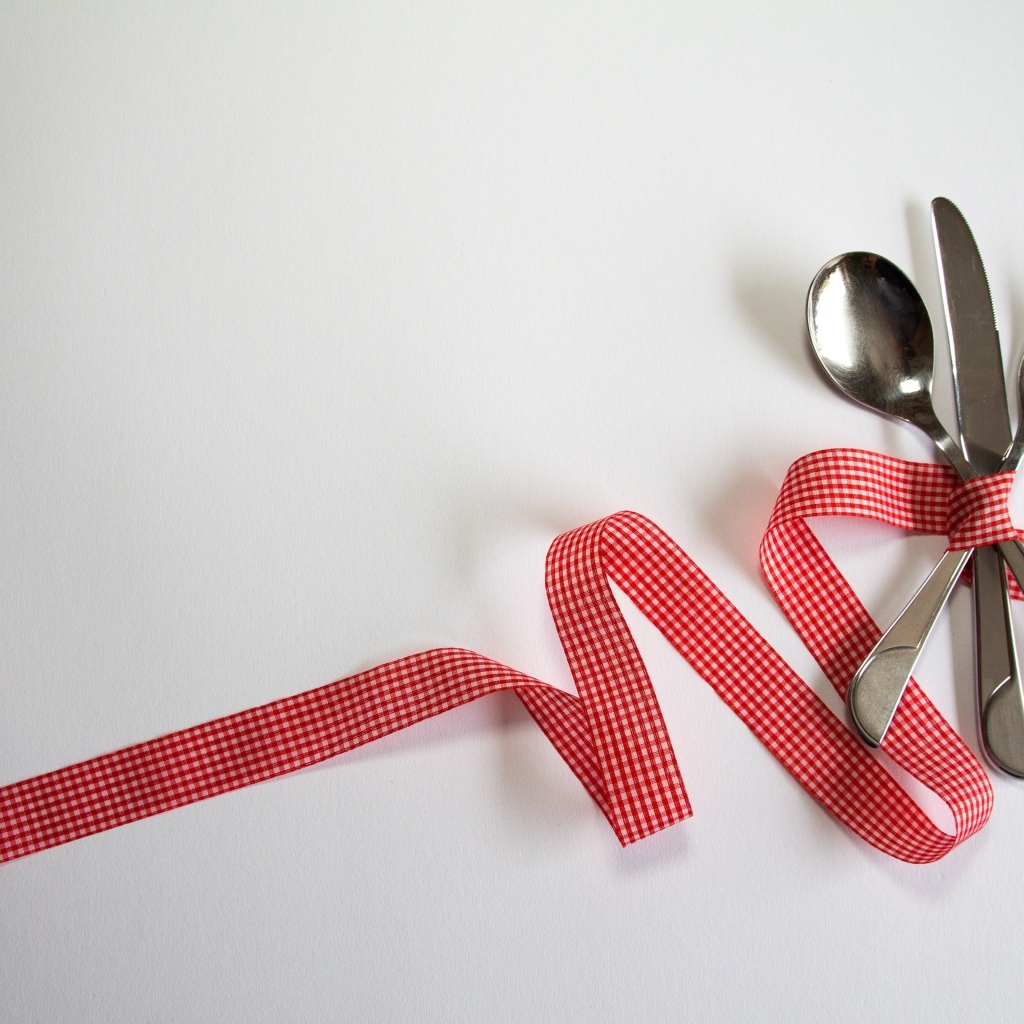 Столовые приборы перевязаны лентой на сером фоне