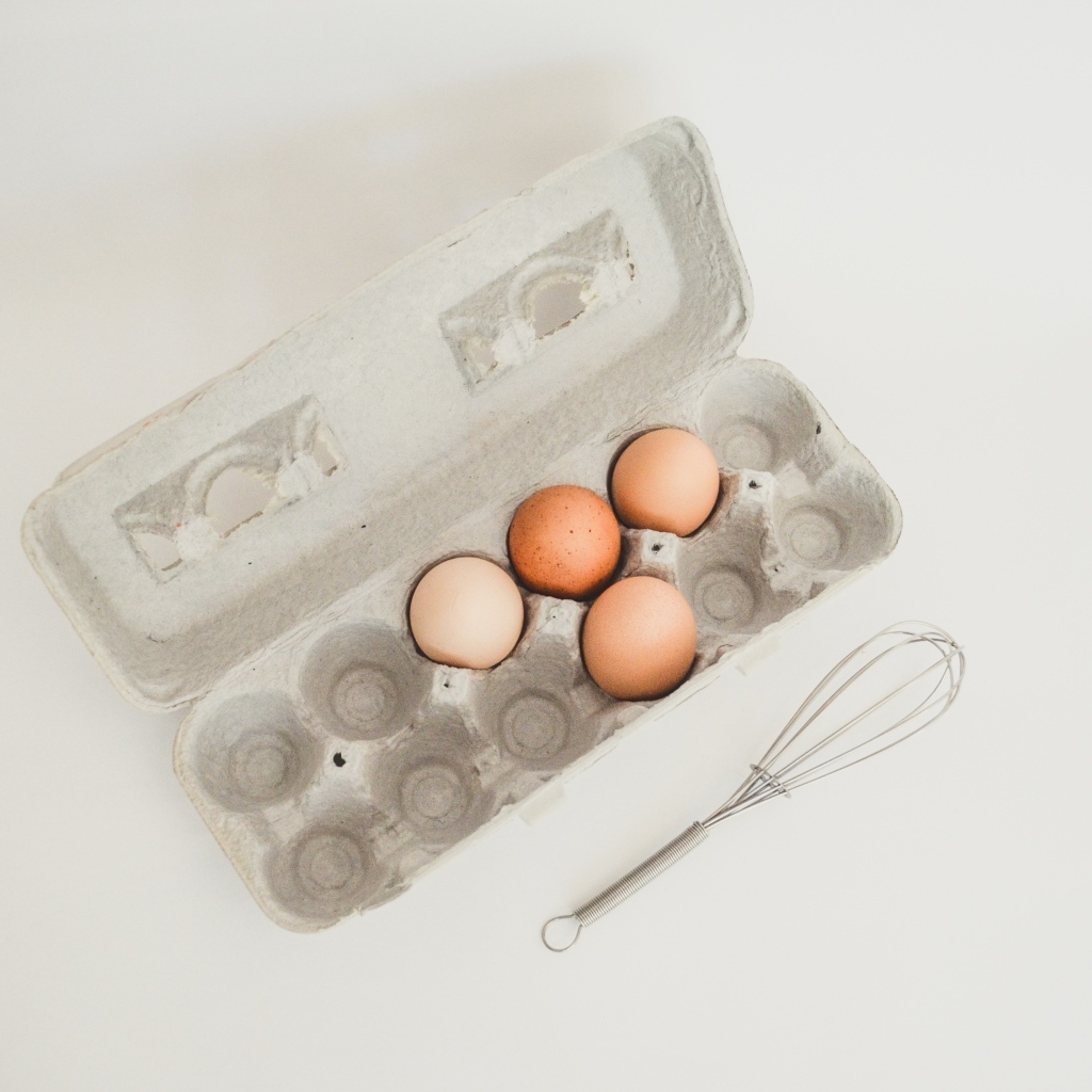 Четыре яйца в лотке на сером фоне