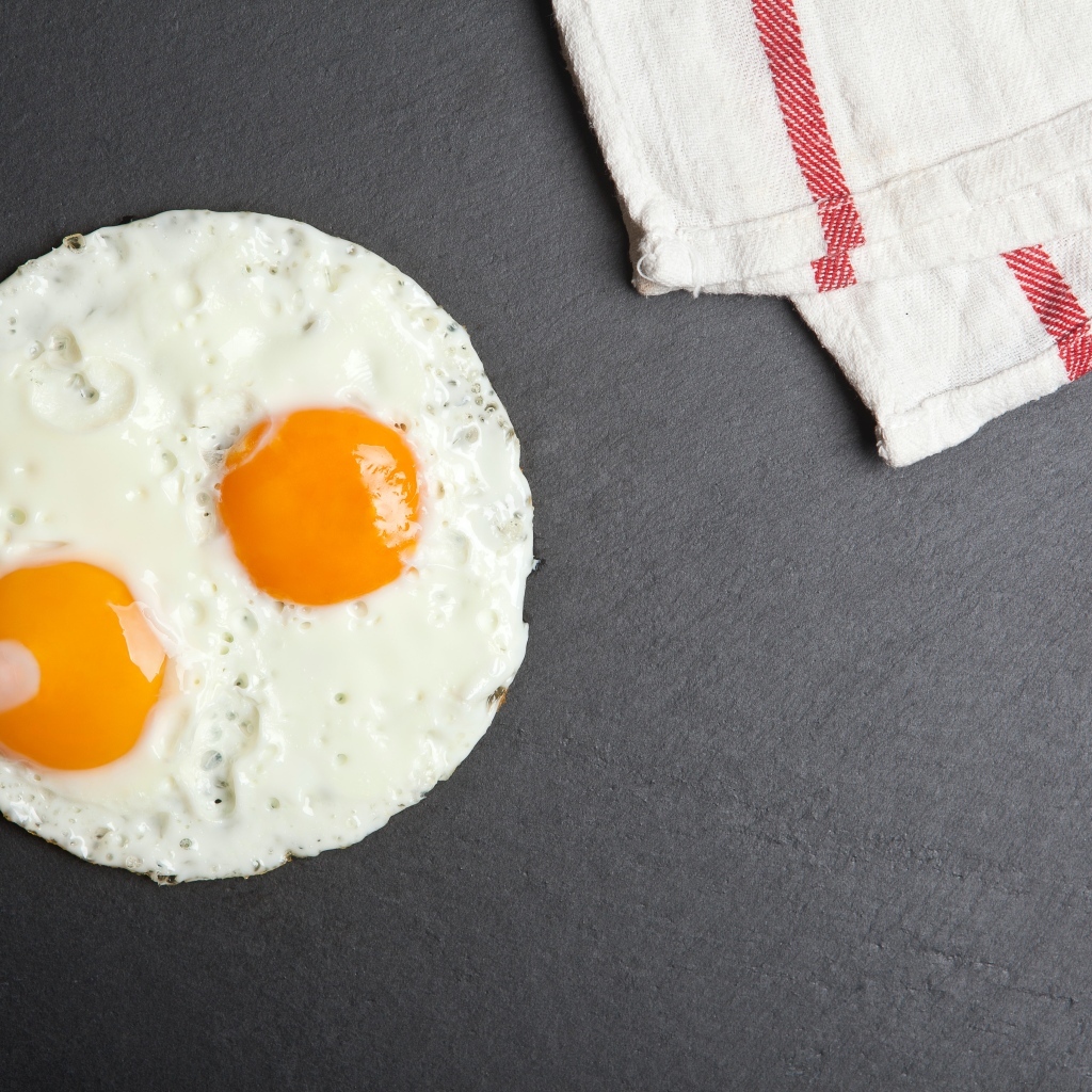 Яичница глазунья на сером столе с полотенцем