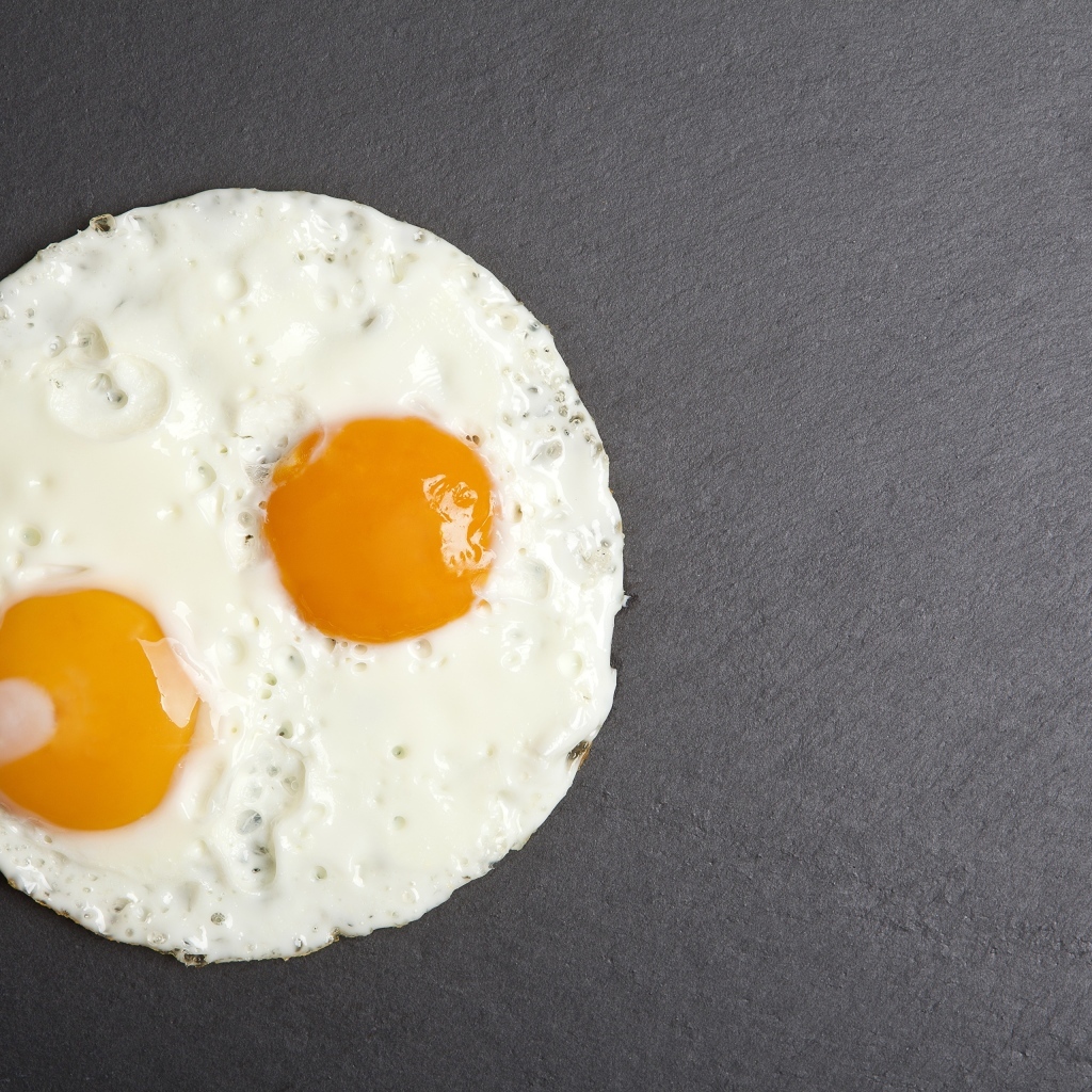 Яичница глазунья с вилкой на сером столе
