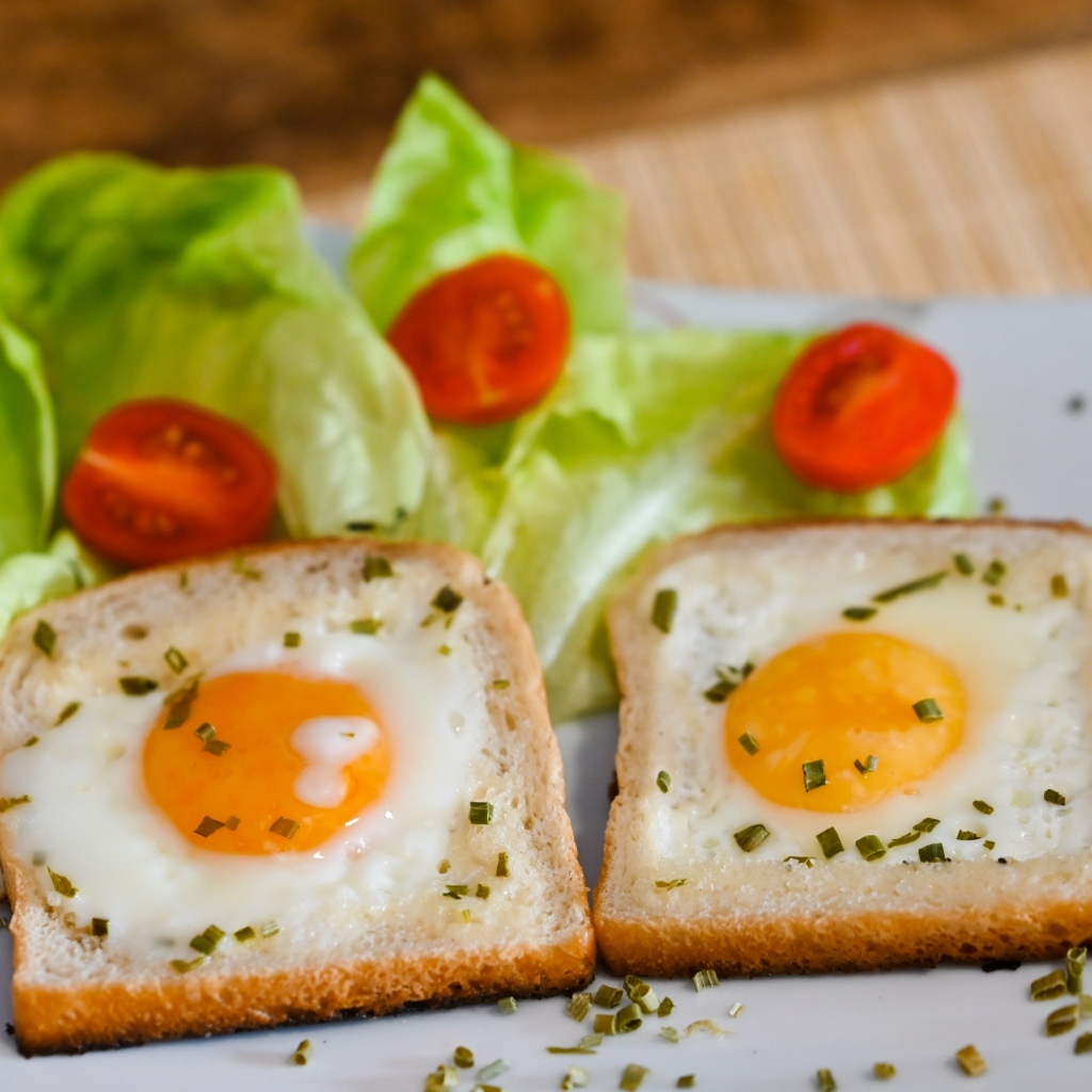 Яичница с хлебом, помидорами и листьями салата на завтрак