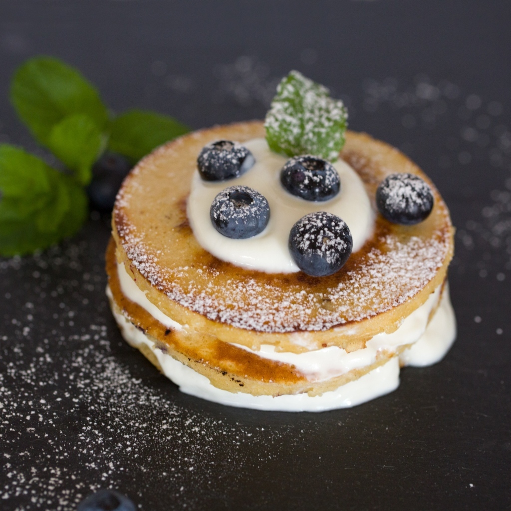 Оладьи с кремом и ягодами черники на столе