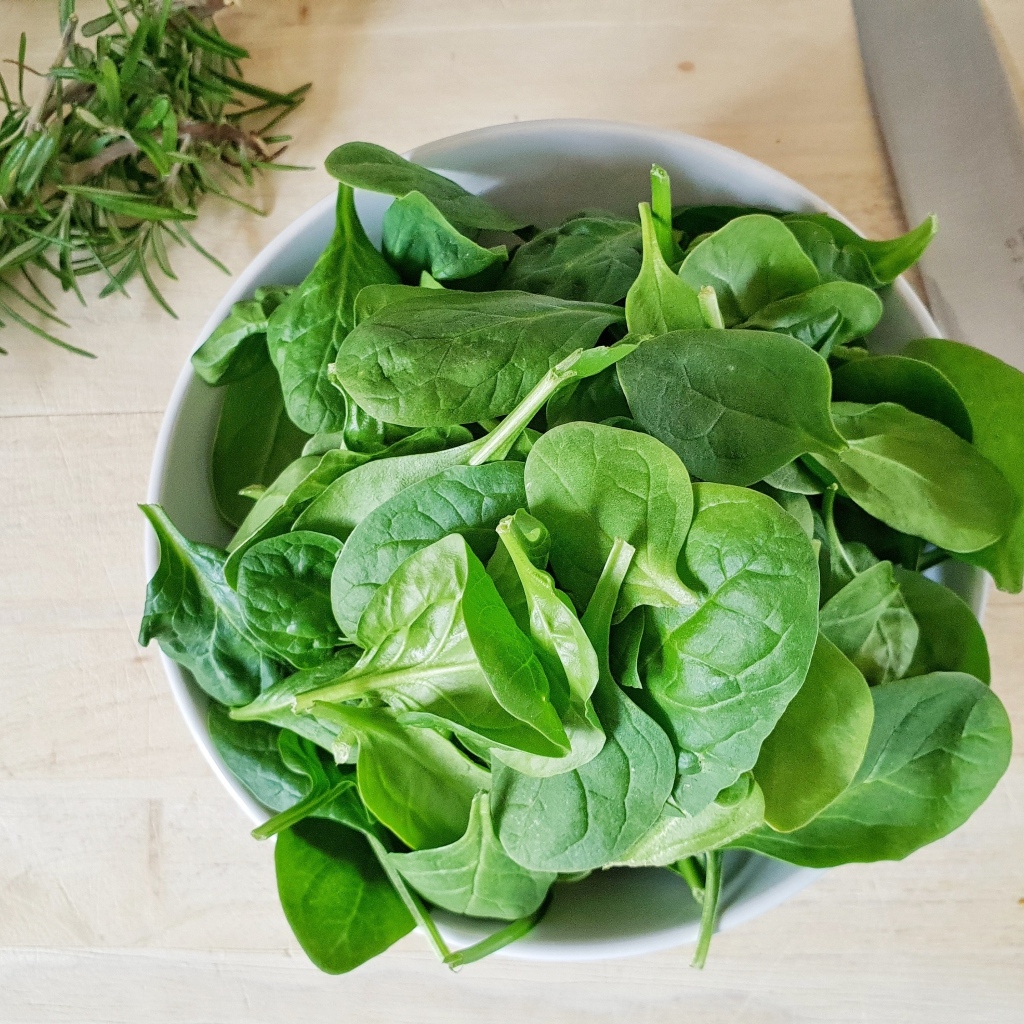 Зеленые листья базилика на столе с розмарином