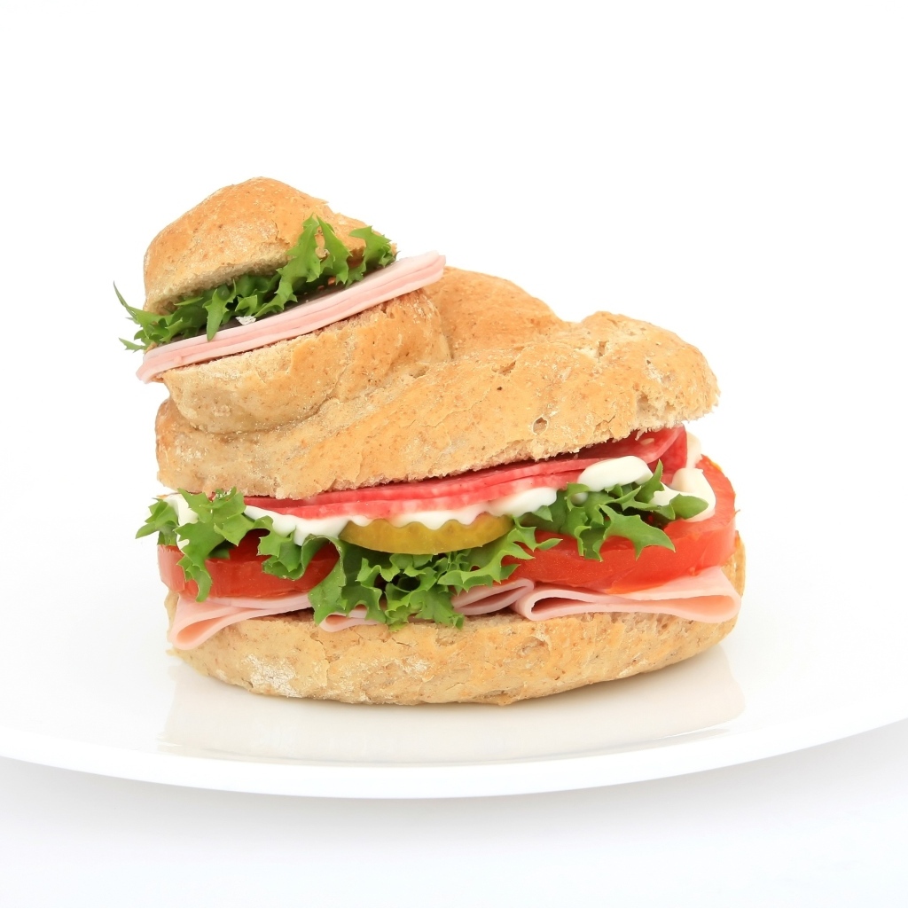 Гамбургер с колбасой, томатами и листьями салата на белом фоне